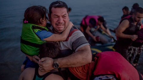 Laith Majid al Amiri cries as he holds his youngest children as they arrived on the Greek island of Kos. 