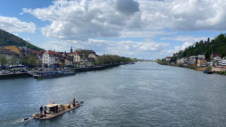 Ein Floß fährt auf dem Neckar durch Heidelberg. 