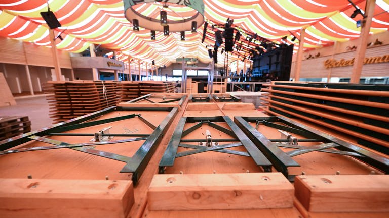 In einem Festzelt auf dem Festgelände Cannstatter Wasen, stehen Bänke und Tische zum Aufbau bereit.
