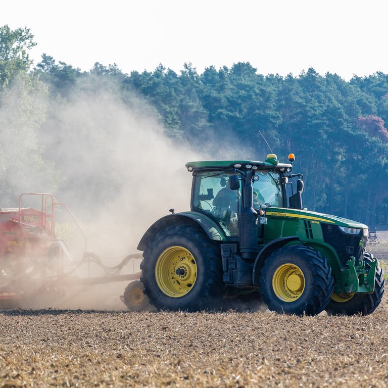 Mit einer an einen Traktor angehängten Drillmaschine sät ein Bauer der Agrargenossenschaft Drebkau Winterraps auf einem trockenenen Feld aus. 