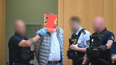 Ein Angeklagter wird in Stuttgart-Stammheim beim Beginn eines Prozesses um Reichsbürger in den Gerichtssaal geführt. (Foto: dpa Bildfunk, picture alliance/dpa/dpa-Pool | Bernd Weißbrod)