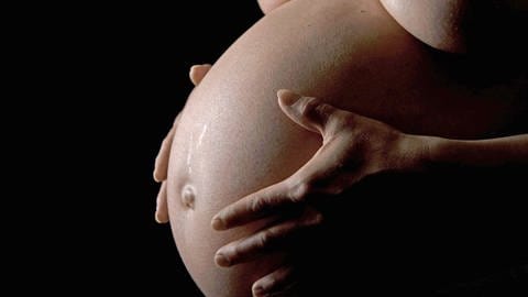 Hochschwangere Frau zeigt ihren Babybauch - Hebammen planen Geburtshaus in Ulm. 