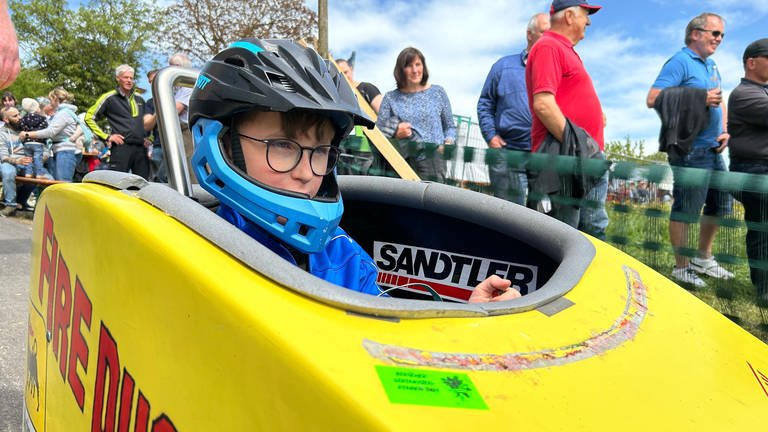 Der 10-jährige Julius Nagel sitzt in seiner Seifenkiste am Start eines Seifenkistenrennens.