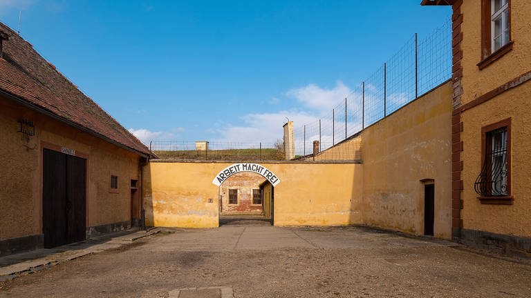 Verwaltungshof im Konzentrationslager Theresienstadt, im Hintergrund das Tor zum Konzentrationslager mit der Aufschrift: Arbeit macht frei