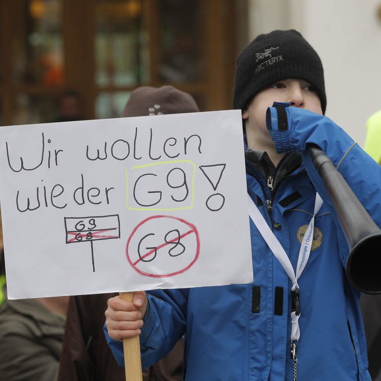 Demonstration für das neunjährige Gymnasium. Ein Junge mit einer Tafel in der Hand und der Aufschrift "Wir wollen wieder G9". 
