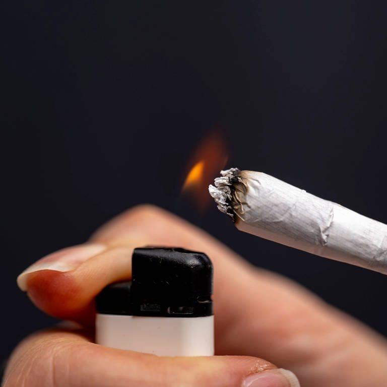 Thema Cannabis-Legalisierung (Symbolbild), Raucherin zündet sich einen Joint an.