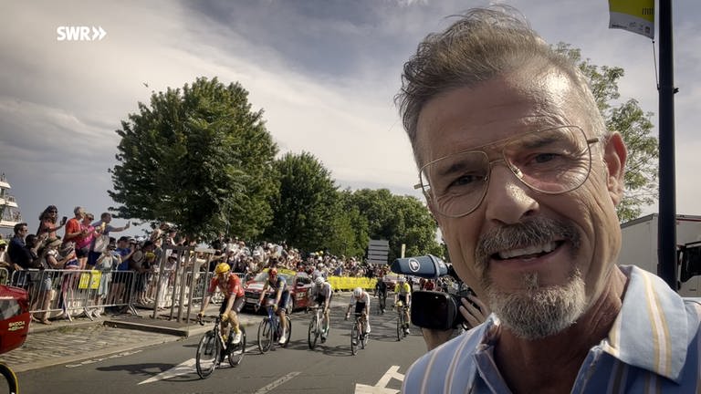 Sportmoderator Michael Antwerpes vor dem Spitzenfeld der Tour de France, das ins Etappenziel einfährt