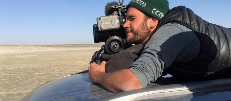 Kameramann Johannes Greisle versucht aus dem Auto heraus einen Sandsturm mit der Kamera einzufangen.